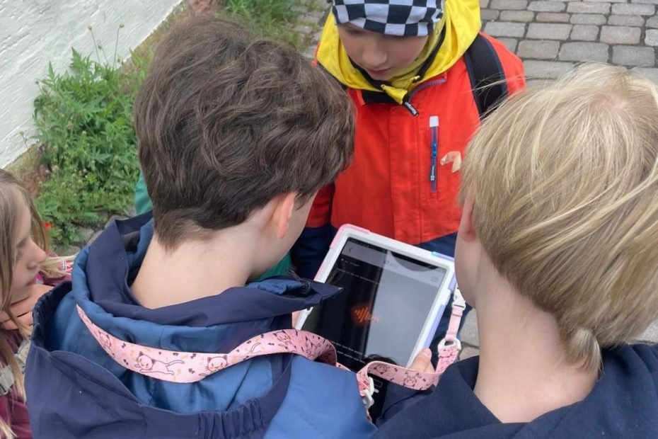 Drei Kinder stehen um ein Tablet
