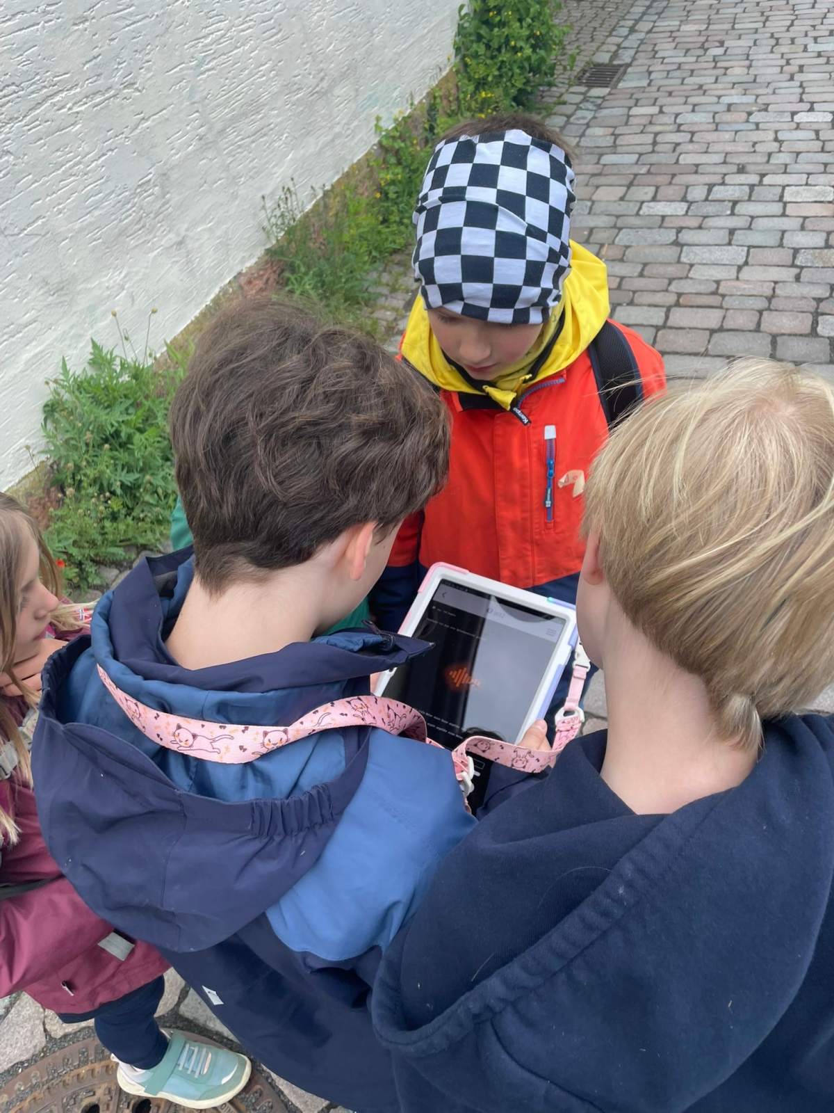 Drei Kinder stehen um ein Tablet